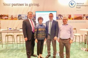 Four professionals stand in front of a conference booth