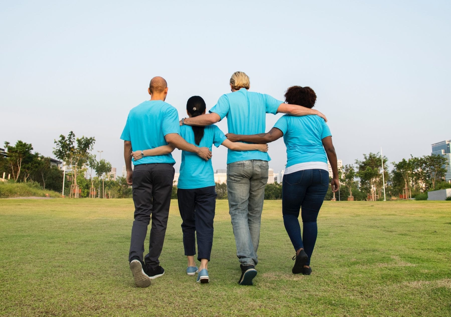Four people walking with arms around each other